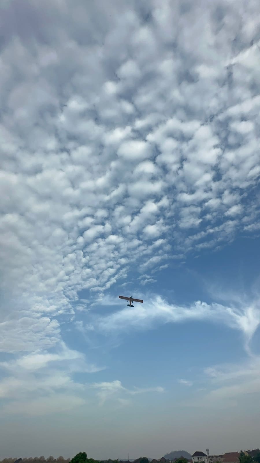 RC aircraft high against a mackerel sky