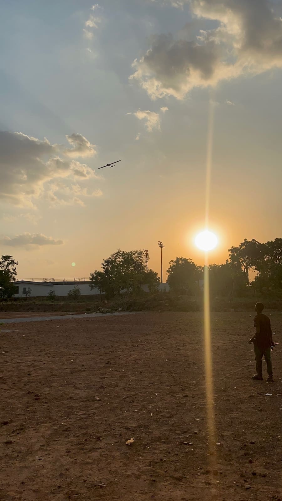 RC aircraft circling overhead as the sun sets over the flying field